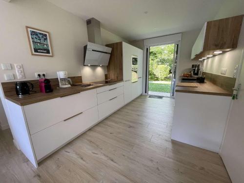 une cuisine avec des armoires blanches et un plancher en bois dans l'établissement Maison rénovée à Fouesnant, proche plages, jardin et terrasse - FR-1-481-167, à Fouesnant