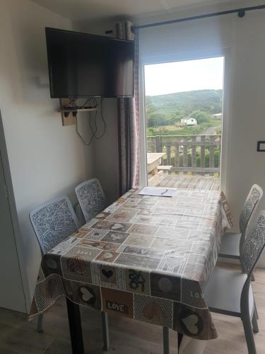 une table avec des chaises et une télévision et un balcon dans l'établissement L échappée belle, à Équihen-Plage