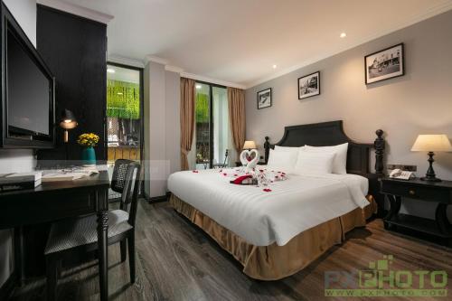 a bedroom with a large bed with a desk and a computer at Paradise Grand Center Hanoi Hotel in Hanoi