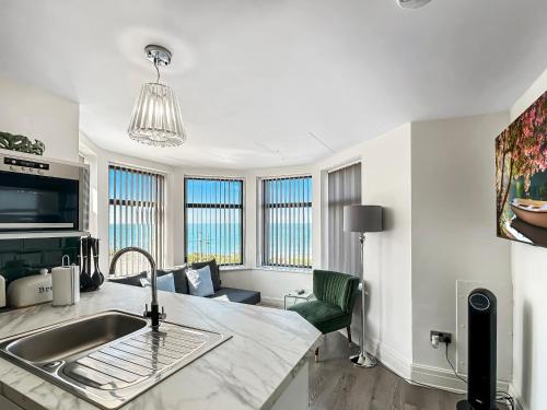 a kitchen with a sink and a living room with windows at Granada Apartments Berkeley in Blackpool