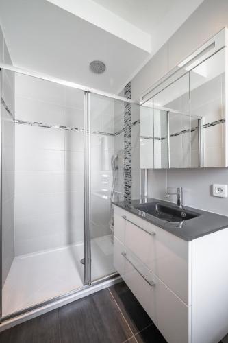 une salle de bain blanche avec un lavabo et une douche dans l'établissement Le Botta, spacieux appartement famillial, centre ville de Menton, jardins Biovès, à 5 minutes de la mer, à Menton