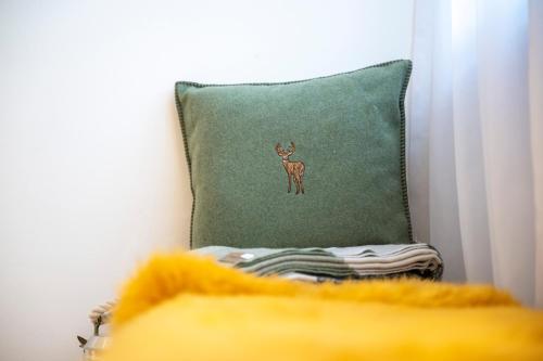 a green pillow with a deer applique on it at Ferienhaus Meis Chalet in Scuol