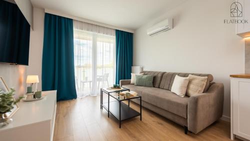 un soggiorno con un divano e una grande finestra di Flatbook Apartamenty - Sztutowo Perła Mierzei a Sztutowo