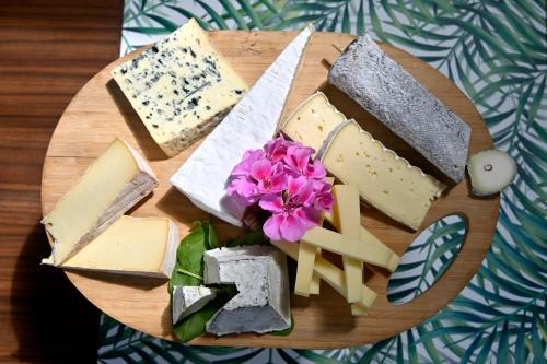 a wooden plate with cheese and flowers on a table at Logis Auberge De Launay in Limeray