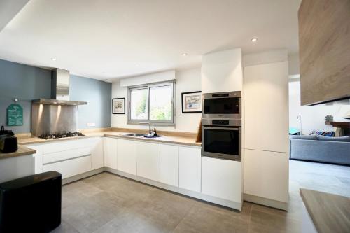 une cuisine avec des armoires blanches et un four à plaques de cuisson dans l'établissement Le cottage bleu - 400 m de la mer - parking, à Larmor-Plage