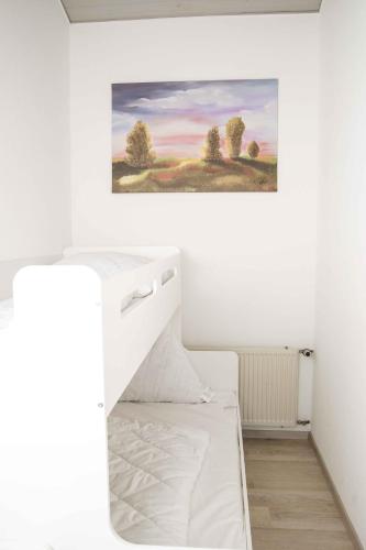 a bedroom with a white bed and a painting on the wall at Ferienhaus Henneglück3 mit Sauna in Meschede