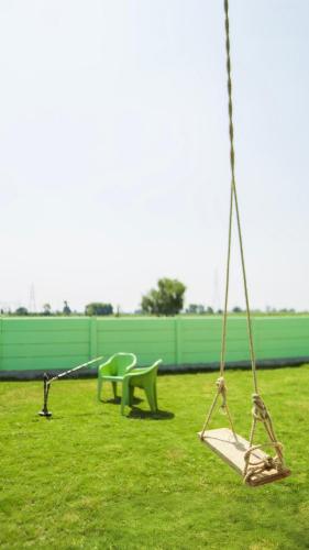 a swing set and a bench in a park at Chaudhary Farm house in Daula
