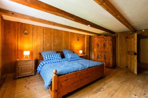 ein Schlafzimmer mit einem Bett und einer Holzwand in der Unterkunft Mit Blick auf Bergwiesen - Familienfreundliches Bauernhaus im Westallgäu in Weiler-Simmerberg
