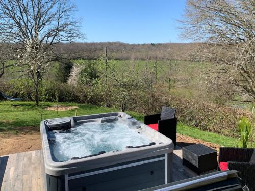 a hot tub on a deck with a view of a field at Chalet et jacuzzi au coeur du Nivernais in Sauvages
