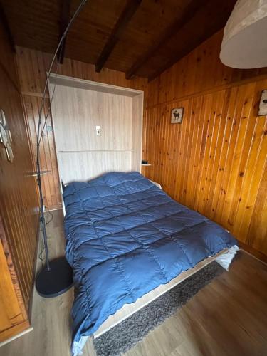 a large blue bed in a room with wooden walls at Chalet et jacuzzi au coeur du Nivernais in Sauvages
