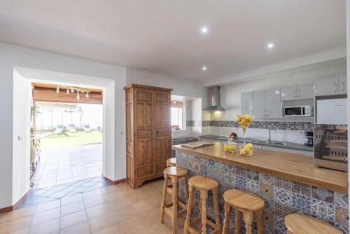 a kitchen with a counter and some stools in it at Casa Rural Maimones in Los Pérez