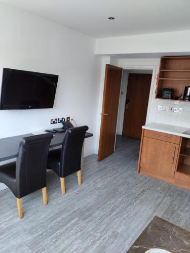 a room with a desk and two black chairs at Roland House in London