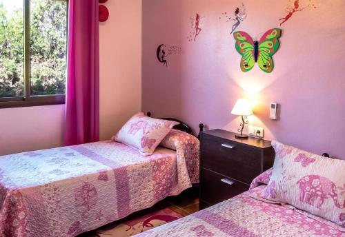 a bedroom with two beds and a butterfly on the wall at Casa Rural Villa Lucrecia in La Lantejuela