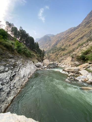a river in the middle of a rocky mountain at Bros Camps & Cafe, Tirthan Valley in Kotla