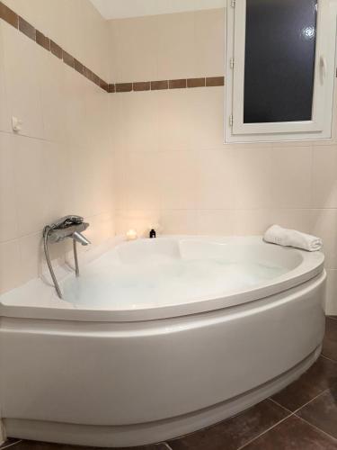 La salle de bains est pourvue d'une baignoire blanche et d'une fenêtre. dans l'établissement Jolie location chez Philippe & Karine, à Linguizzetta