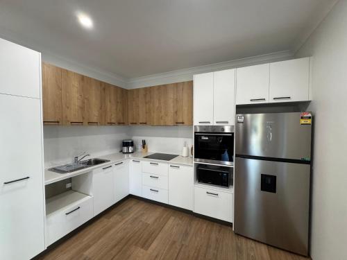 a kitchen with white cabinets and a stainless steel refrigerator at Shoreline Escape in South Beach