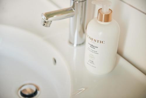 a white bottle of detergent sitting on a bathroom sink at Hotell Björkhaga in Mullsjö