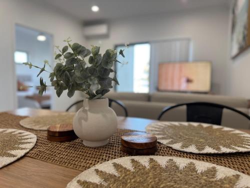 a table with a white vase with a plant in it at Shoreline Escape in South Beach