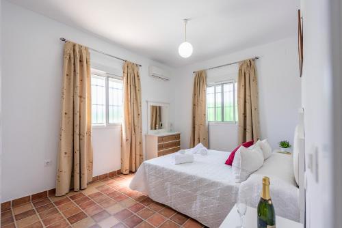 ein weißes Schlafzimmer mit einem Bett und einem Spiegel in der Unterkunft Casa Brisa del Valle in Sevilla