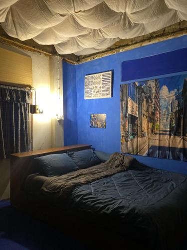 a blue bedroom with a bed with a blue wall at HostelBed and Art Space Phichai in Phichai