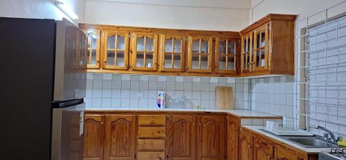 a kitchen with wooden cabinets and a black refrigerator at Sleeping Bueaty Gest House in Soufrière