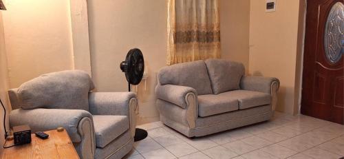a living room with two chairs and a chair and a table at Sleeping Bueaty Gest House in Soufrière
