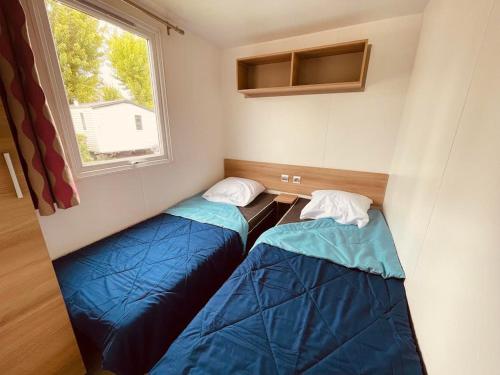 deux lits dans une petite pièce avec une fenêtre dans l'établissement Mobil Home Bouginvilliers 4, à Valras-Plage