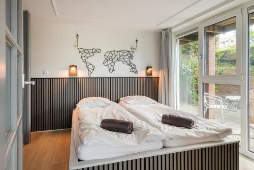 Un dormitorio con una cama blanca y una ventana. en Wasser - Modern Beach house, en Bergen aan Zee