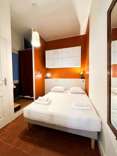 une chambre avec un grand lit blanc avec des murs orange dans l'établissement Le Simone, à Sète
