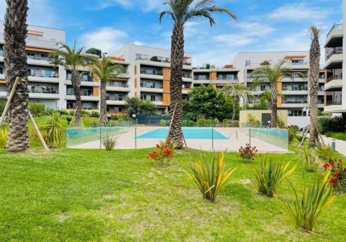 un complexe d'appartements avec piscine et palmiers dans l'établissement Appartement toit terrasse, piscine, plages à 10min et parking, à Fréjus