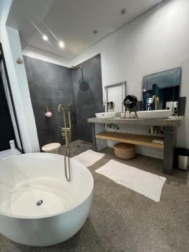 a bathroom with a white tub and two sinks at Helder Haven Cottage in Somerset West