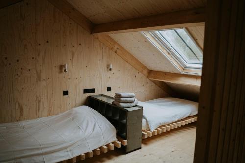 an attic room with two beds and a window at Bed en Brood in de Kapschuur - Boerderij de ZuiderKRIB in Kraggenburg