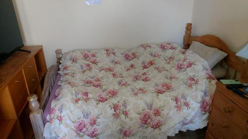 a bed with a pink and white comforter on it at Phoenix Nights Guest House in Barrow in Furness