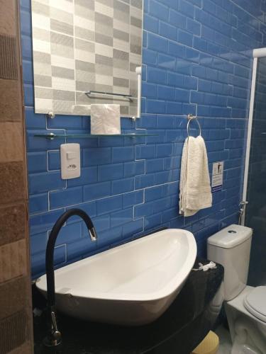 a blue tiled bathroom with a tub and a toilet at Hostel e pousada paz e benção in Mossoró
