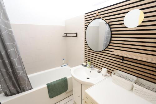 une salle de bain avec une baignoire, un lavabo et un miroir dans l'établissement Appartement 4 personnes avec terrasse au golf de St Cyprien, à Saint-Cyprien