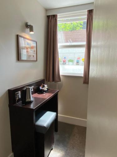 a room with a desk and a window with a sink at Trebovir Hotel in London