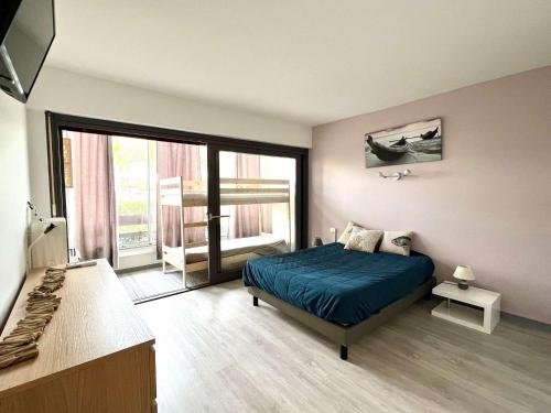 une chambre avec un lit bleu et une grande fenêtre dans l'établissement 3 pièces climatisé avec terrasse, parking privé, à 100m de la plage, 7 couchages - FR-1-307-148, au Grau-du-Roi