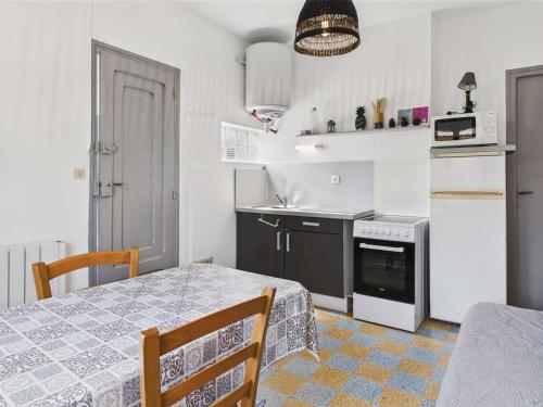 Il comprend une cuisine équipée d'une table et d'un réfrigérateur. dans l'établissement Appartement RDC 5 pers avec grande terrasse sud, proche marché, animaux admis - Marseillan Plage - FR-1-326-712, à Marseillan