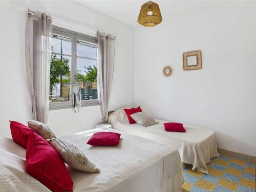 deux lits dans une chambre avec des oreillers rouges dans l'établissement Appartement RDC 5 pers avec grande terrasse sud, proche marché, animaux admis - Marseillan Plage - FR-1-326-712, à Marseillan