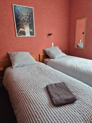 two beds in a room with red walls at Gîte Bîn Vendüd Châ Nous in Le Monastier sur Gazeille