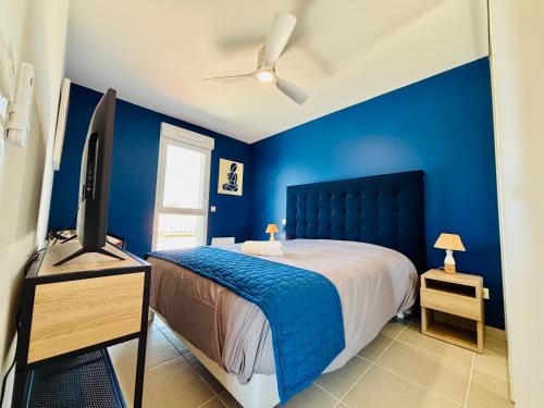 - une chambre bleue avec un lit et une télévision à écran plat dans l'établissement Haut Standing ACCÈS DIRECT MER 3min à pieds,Parking privée, Wifi, Netflix, à Vias