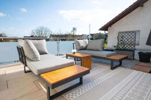 a patio with two couches and tables on a balcony at Lilias Ferienwohnung in Losheim