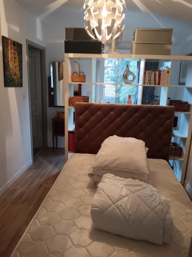 un lit avec une tête de lit brune dans une chambre dans l'établissement Cottage à 600 mètres du Lac de Sanguinet, à Sanguinet