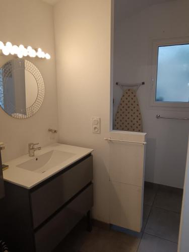 une salle de bain avec un lavabo et un miroir dans l'établissement Cottage à 600 mètres du Lac de Sanguinet, à Sanguinet