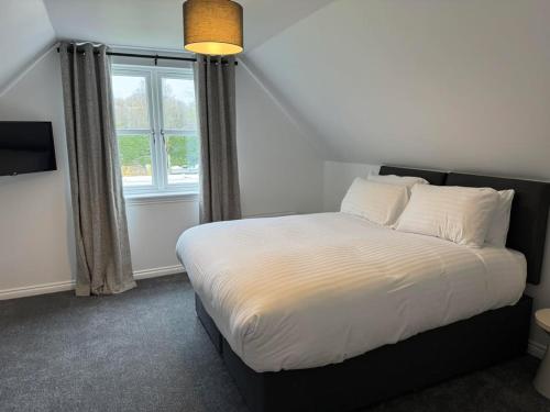 a bedroom with a white bed with a window at The Inn At Charlestown in Dunfermline