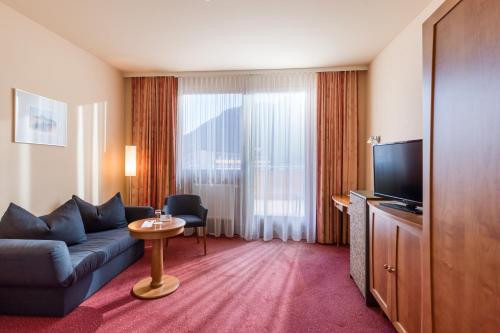 a hotel room with a couch and a television at Vivea Hotel Bad Bleiberg in Bad Bleiberg