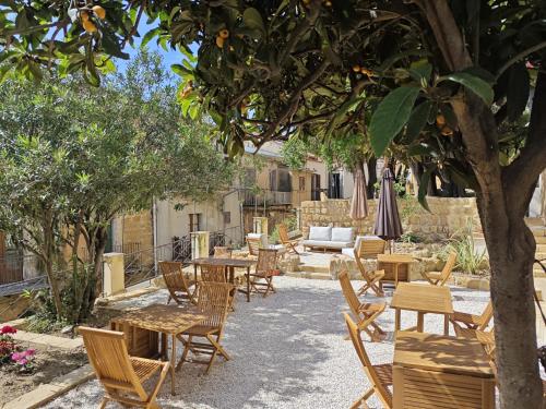 a patio with tables and chairs under a tree at Villa Amoroso - Ospitalità Mediterranea in Agrigento