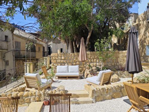 a patio with chairs and umbrellas and a stone wall at Villa Amoroso - Ospitalità Mediterranea in Agrigento