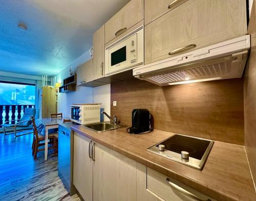 une cuisine avec un évier et un micro-ondes dans l'établissement appartement 4 personnes au coeur de la station des carroz d arâches, à Arâches-la-Frasse