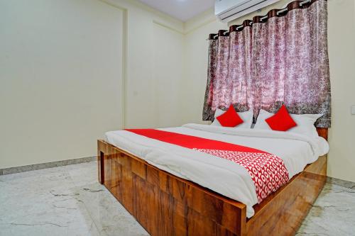 Un dormitorio con una cama grande con almohadas rojas. en Hotel O BlueBird Service Apartment, en Nagpur